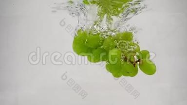 成熟的绿葡萄掉进纯净的水中，冒出气泡。白底慢动作的葡萄浆果。